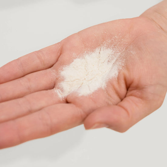 Close-up of Vanessa Megan Prebiotic + C Exfoliating Powder in hand showing ultra-fine, active botanical texture.