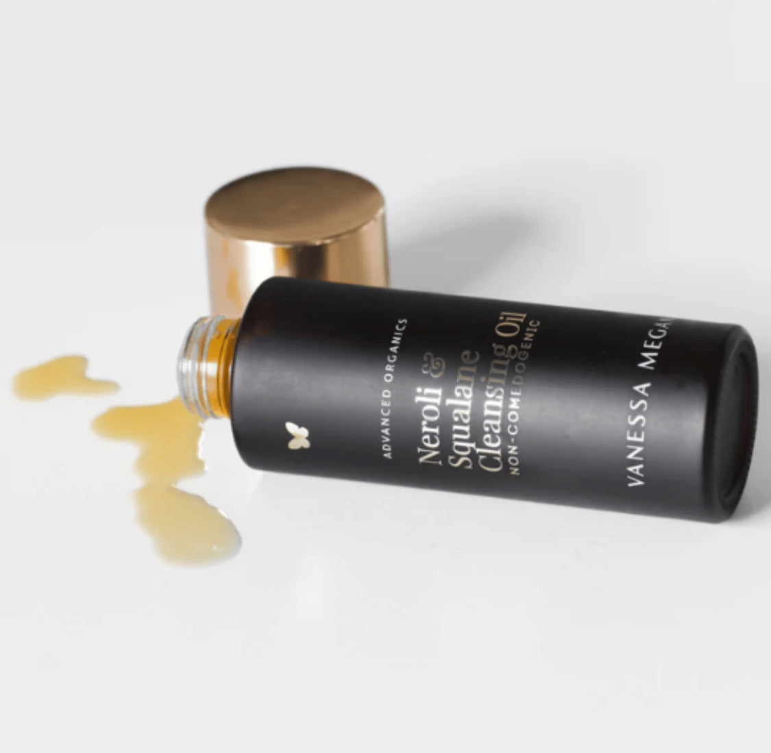 Vanessa Megan Neroli and Squalane Cleansing Oil bottle with spilled oil on white background.