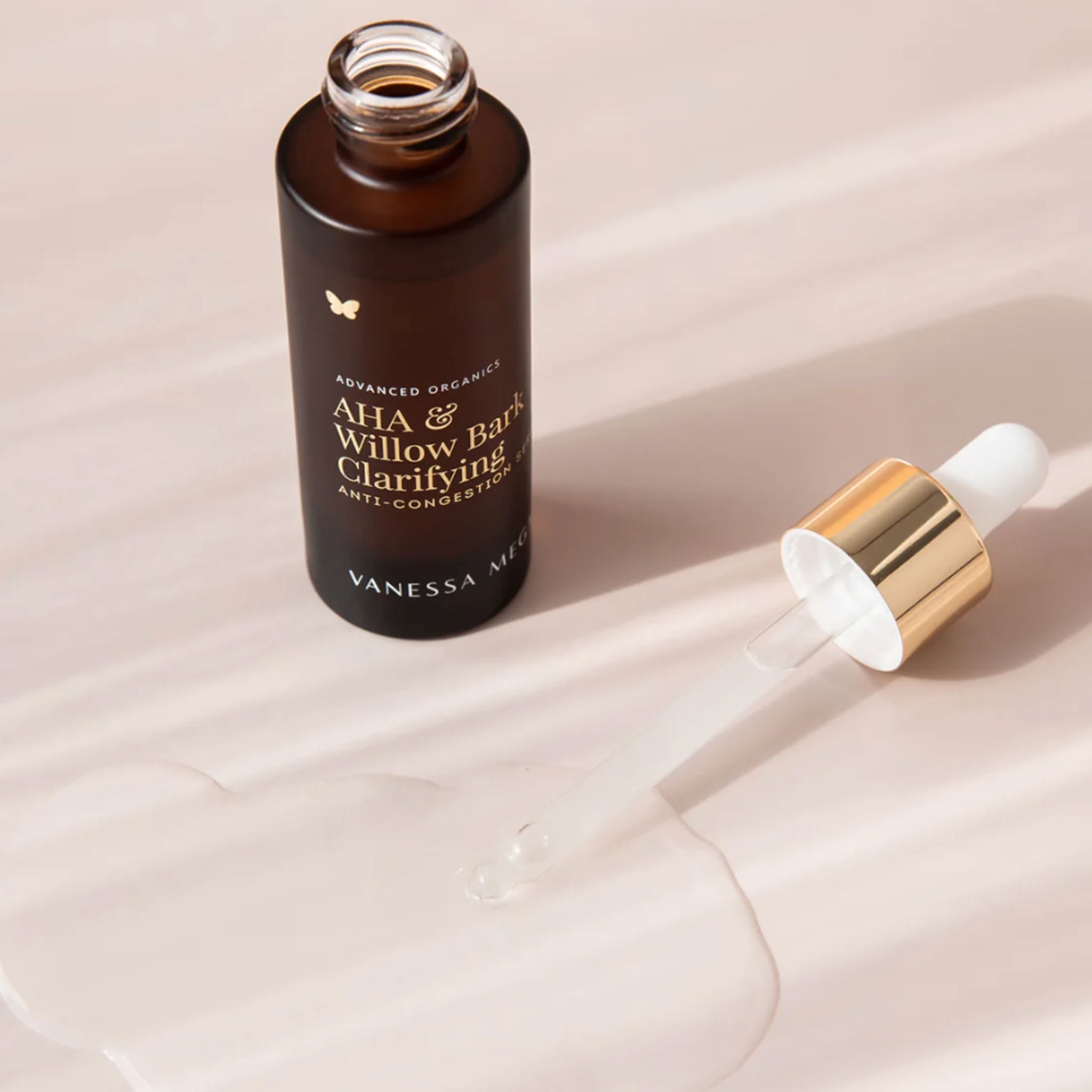 Vanessa Megan AHA and Willow Bark Clarifying Serum open bottle with glass dropper and  shot of the clear serum texture.