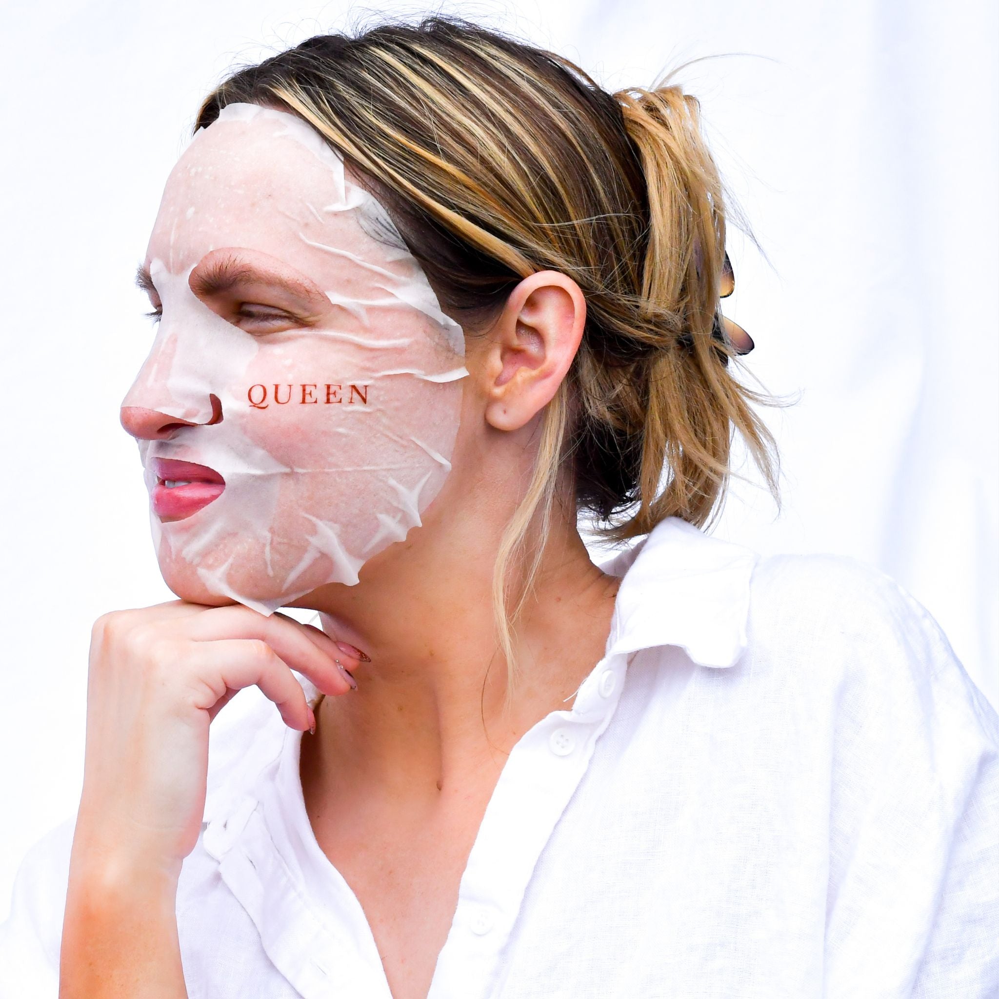 Woman wearing Vanessa Megan Blue Tansy and Cypress Soothing Sheet Mask applied to face, hydrating calming treatment mask fitted to skin while relaxing indoors.