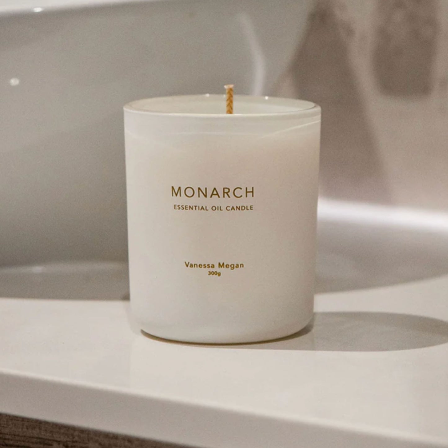 Vanessa Megan Monarch 100% Natural Soy Wax Candle on a bathroom counter, housed in a white glass jar with a visible cotton wick, ready to be lit.