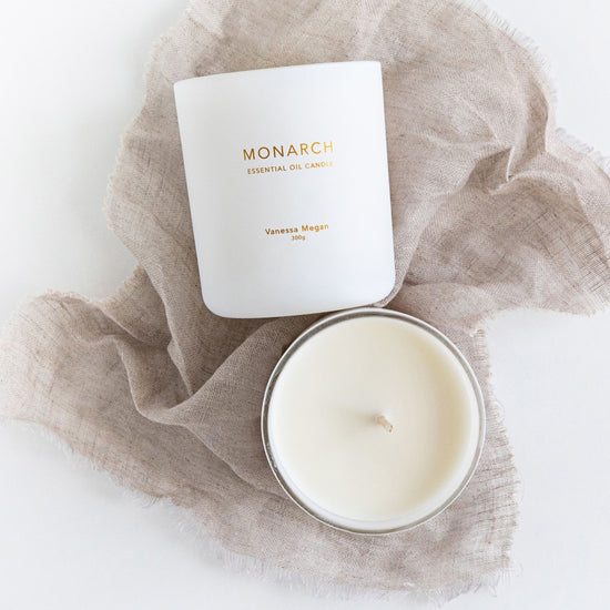 Vanessa Megan Monarch 100% Natural  Essential Oil Soy Wax Candle styled on soft neutral fabric, shown with lid off to reveal smooth wax and centered cotton wick.