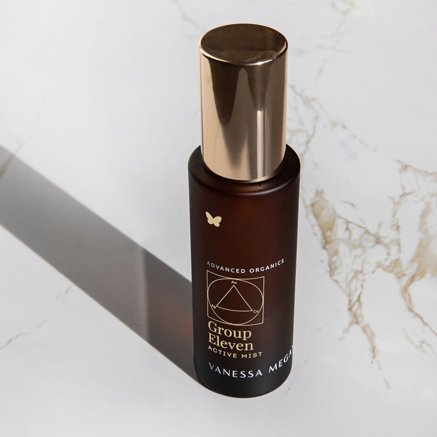 Vanessa Megan Group Eleven Active Mist hydrating facial mist in amber glass bottle with gold cap on marble background.