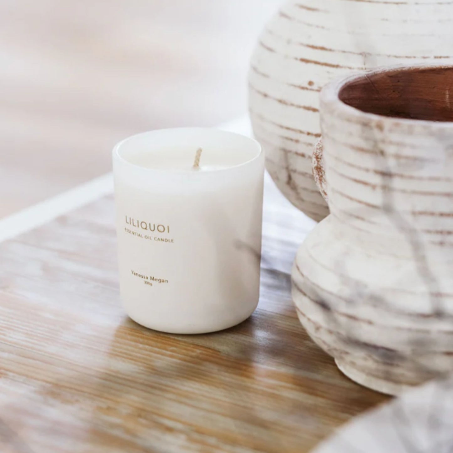Vanessa Megan Liliquoi 100% Natural Soy Wax Candle styled on a timber surface beside ceramic vessels, creating a calm, earthy setting.