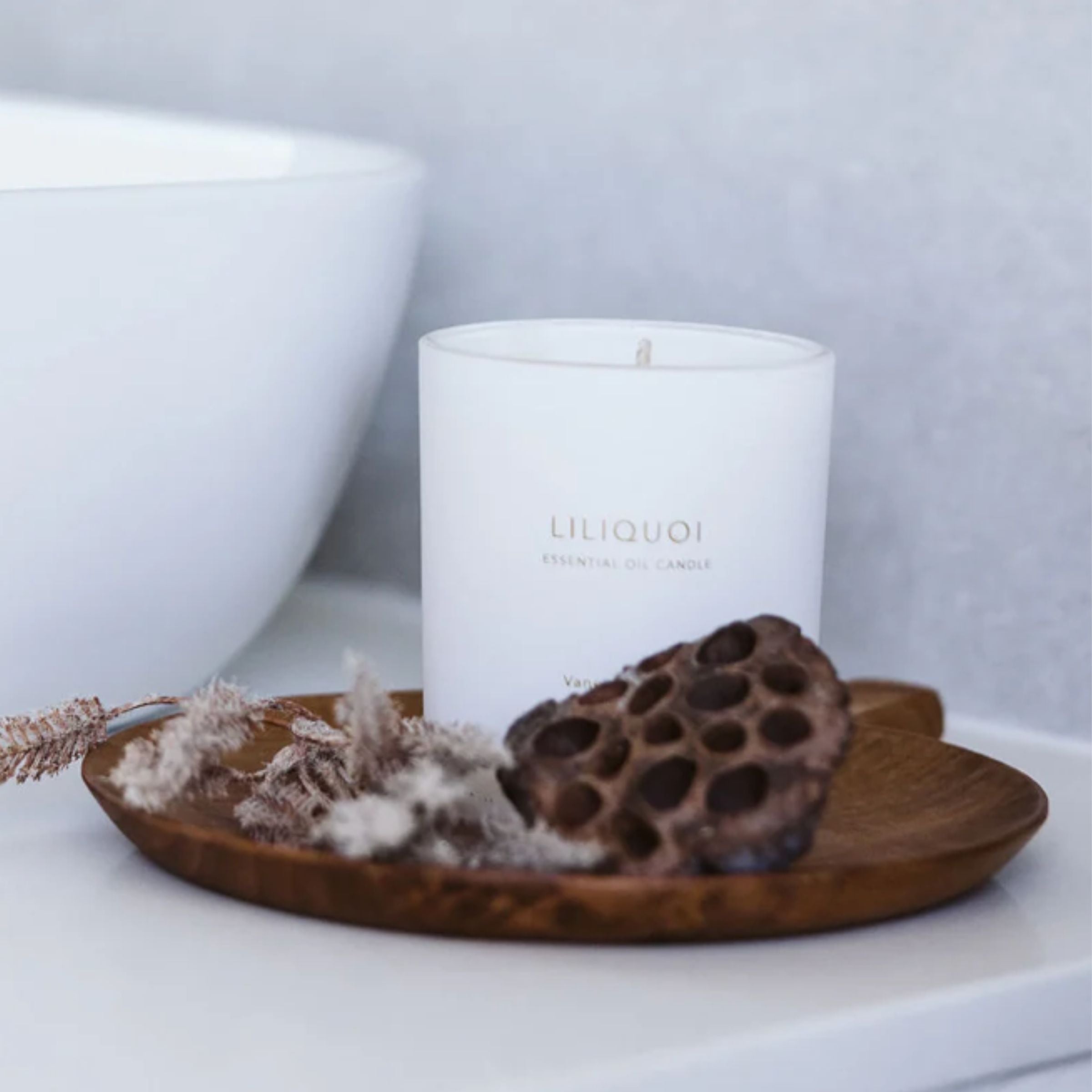 Vanessa Megan Liliquoi 100% Natural Soy Wax Candle styled in a minimalist bathroom with earthy botanicals on a wooden dish, evoking calm and natural elegance.