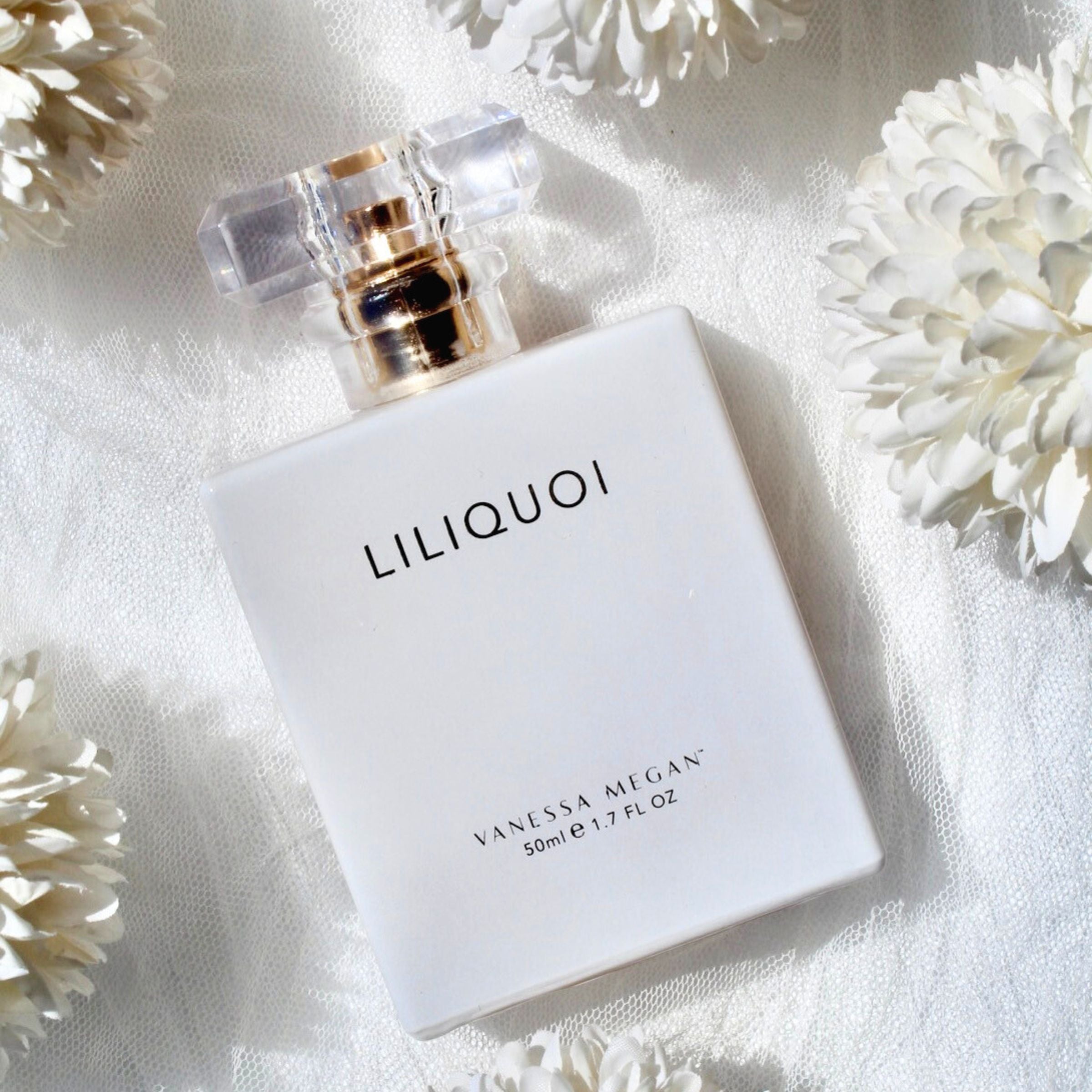 Award-winning Vanessa Megan Liliquoi 100% Natural Perfume styled on soft white fabric with white flowers.