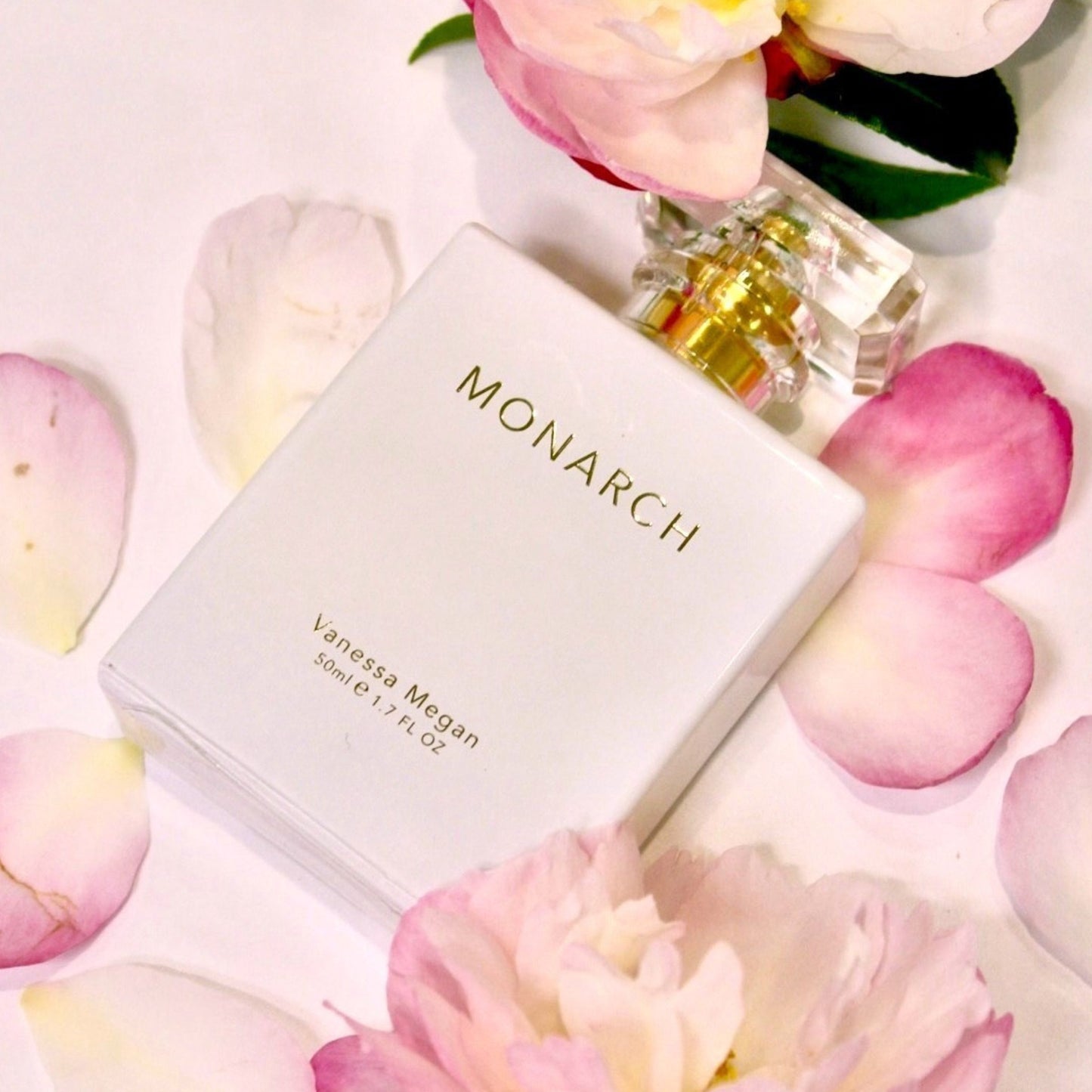 Monarch Perfume bottle by Vanessa Megan surrounded by soft pink rose petals.