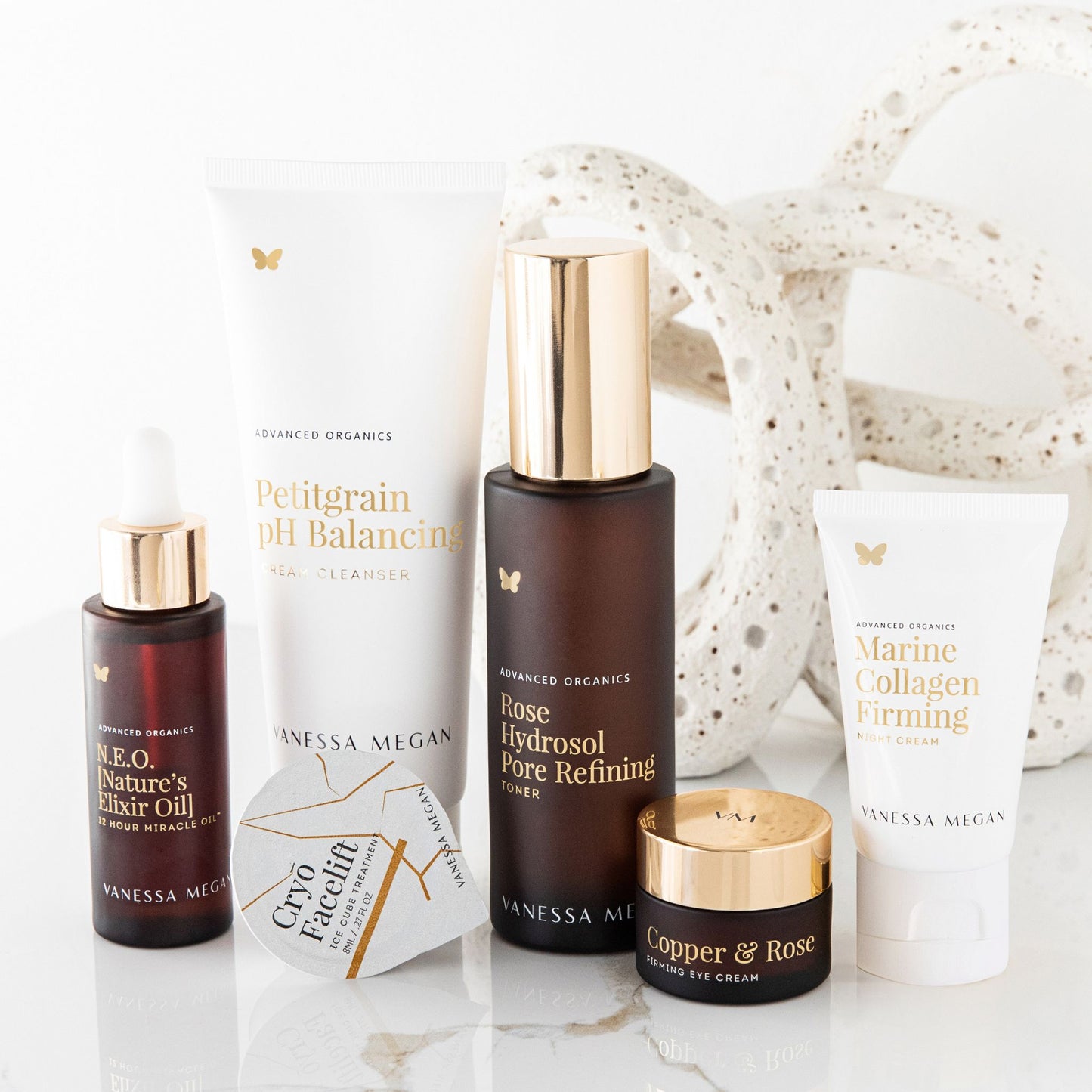 Group of Vanessa Megan Advanced Organics skincare products featuring the 180ml Petitgrain pH Balancing Cream Cleanser alongside the Rose Hydrosol Pore Refining Toner, Marine Collagen Firming Night Cream, Copper & Rose Firming Eye Cream, N.E.O. [Nature’s Elixir Oil], and Cryo Facelift Ice Cube Treatment. A complete natural skincare ritual for balance, clarity and radiance.