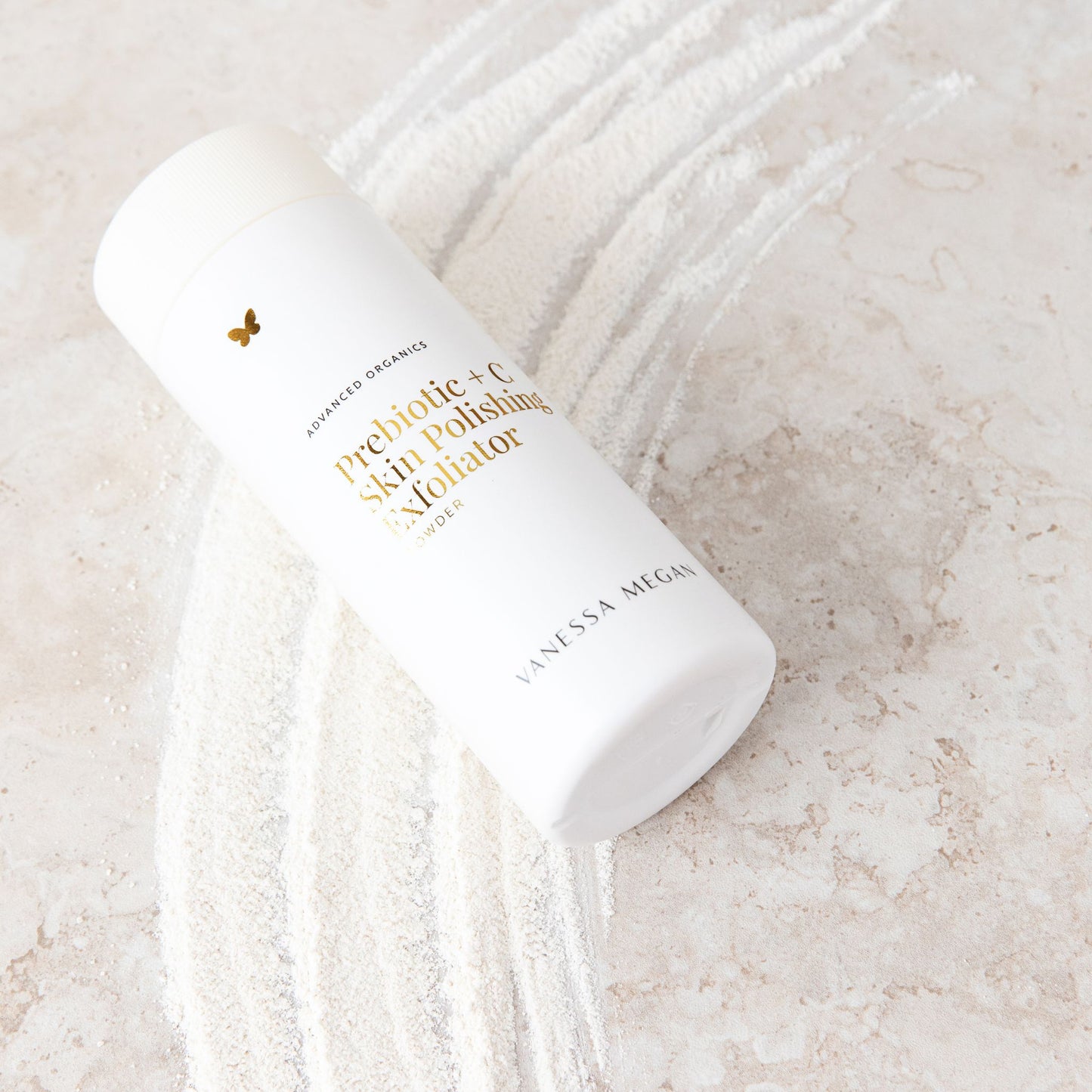 Vanessa Megan Prebiotic + C Skin Polishing Exfoliating Powder 75g in powder dispenser on stone surface with product sample beneath.