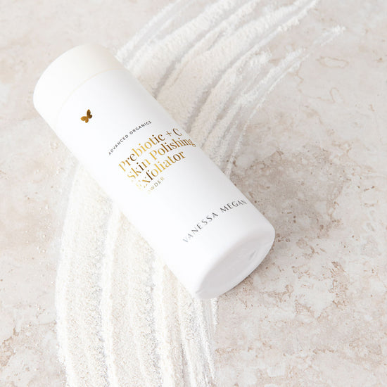 Vanessa Megan Prebiotic + C Skin Polishing Exfoliating Powder 75g in powder dispenser on stone surface with product sample beneath.