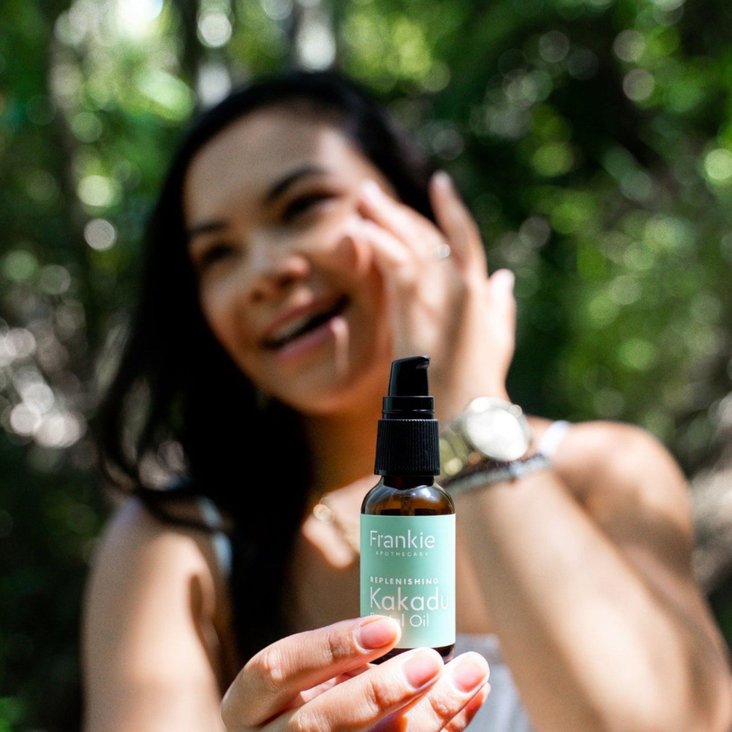 Women holding and applying the Frankie Apothecary Kakadu Replenishing Kakadu Facial Oil to her face.