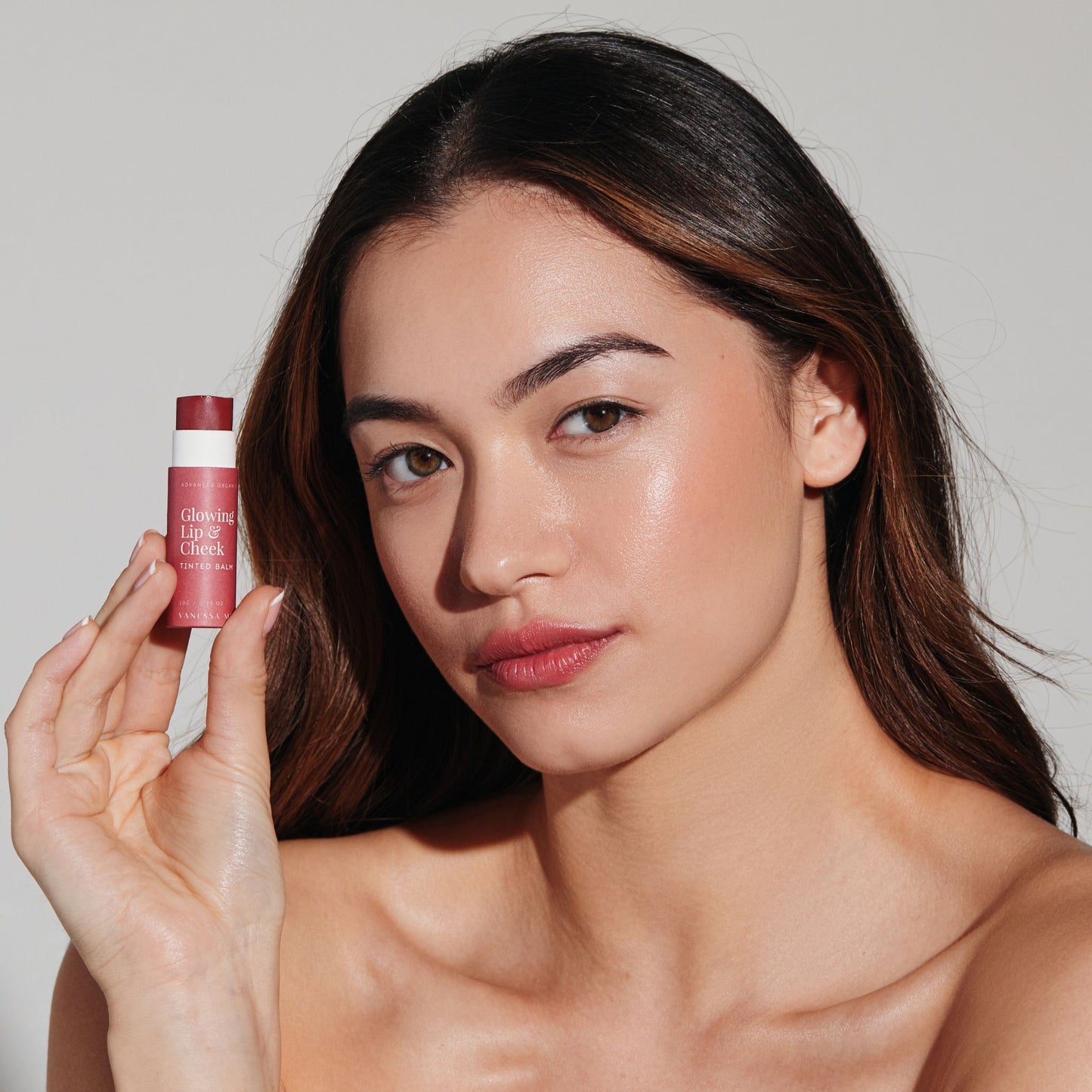 Women Holding the Vanessa Megan Glowing Lip and Cheek Tinted Balm held beside face, clean organic tinted balm for lips and cheeks delivering a sheer radiant buildable flush of natural colour.