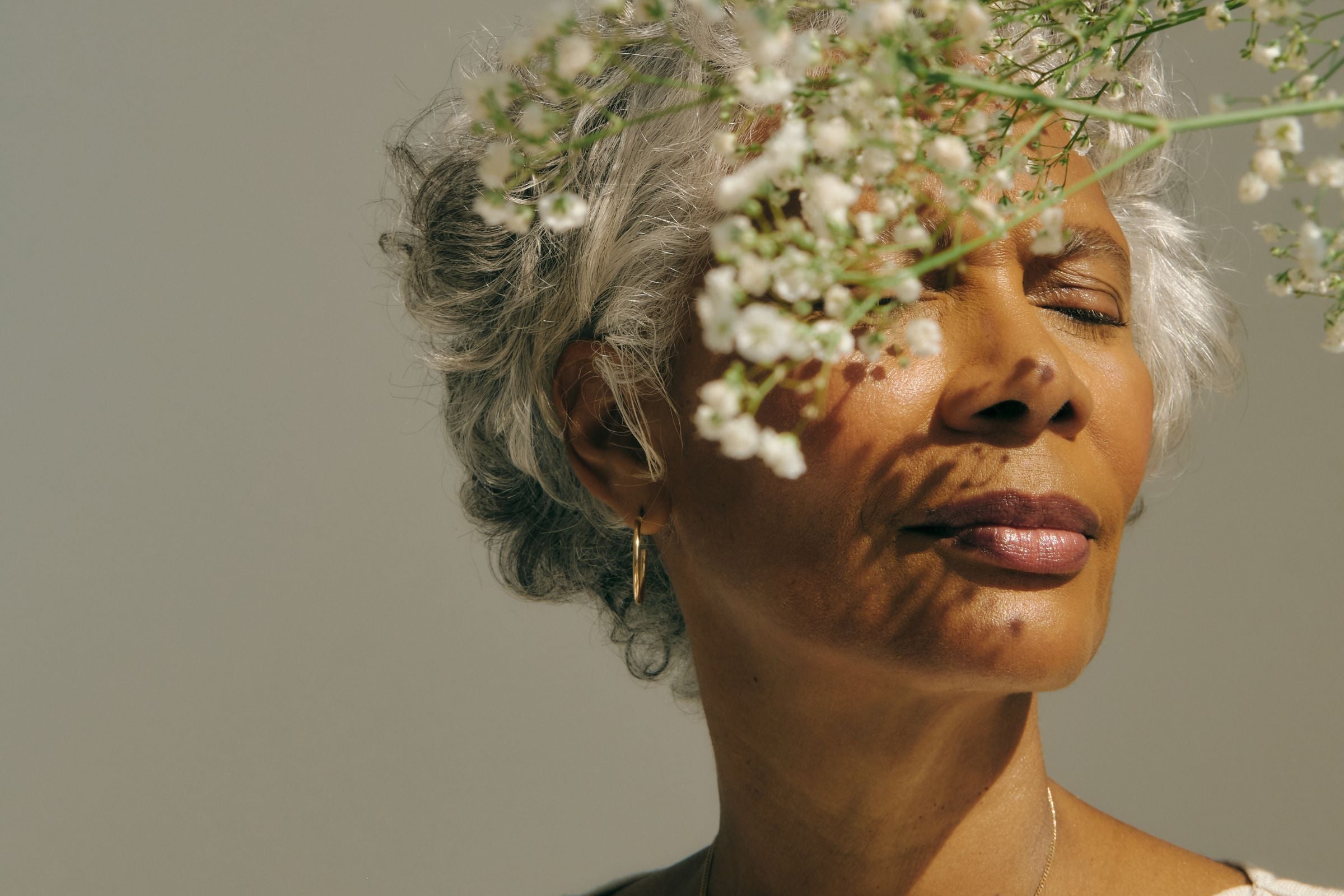 Women with calm face behind flower in natural light 