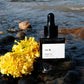 vēr वेर Face Oil placed by a river with vibrant marigolds, representing its nature-infused, holistic skincare benefits for radiant, youthful skin.