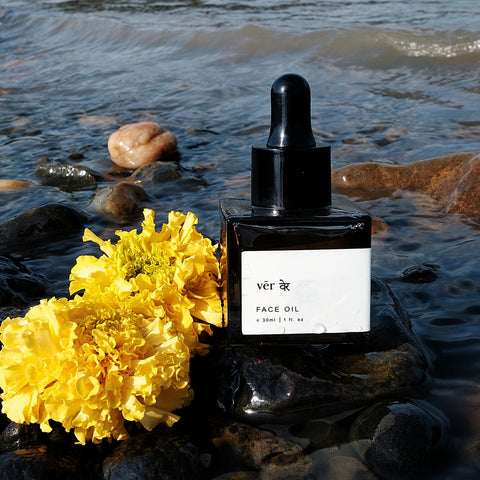vēr वेर Face Oil placed by a river with vibrant marigolds, representing its nature-infused, holistic skincare benefits for radiant, youthful skin.